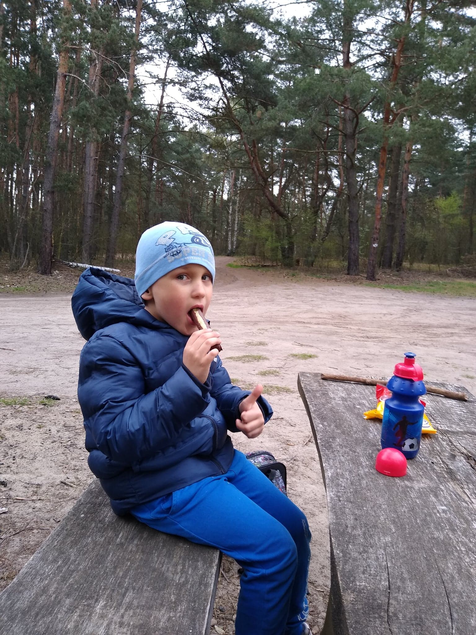 Natan zajada chrupkę na łąwce w lesie
