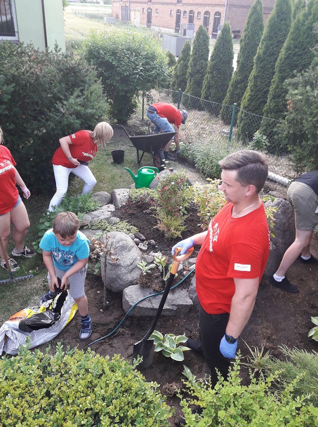 wolontariusze oraz Julek pracują w ogrodzie