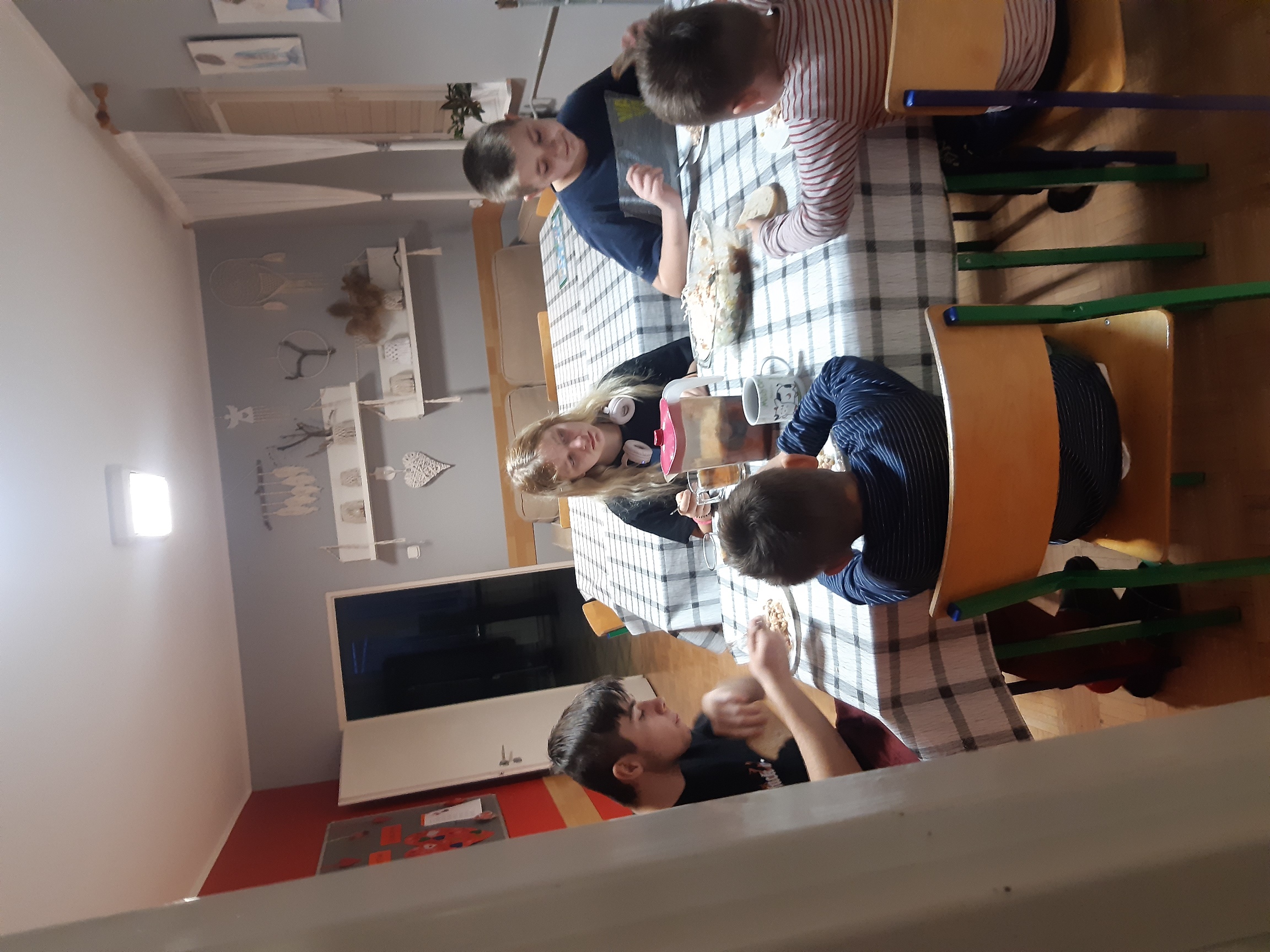 wychowankowie siedzą przy stole i jedzą przygotowaną przez siebie sałatkę