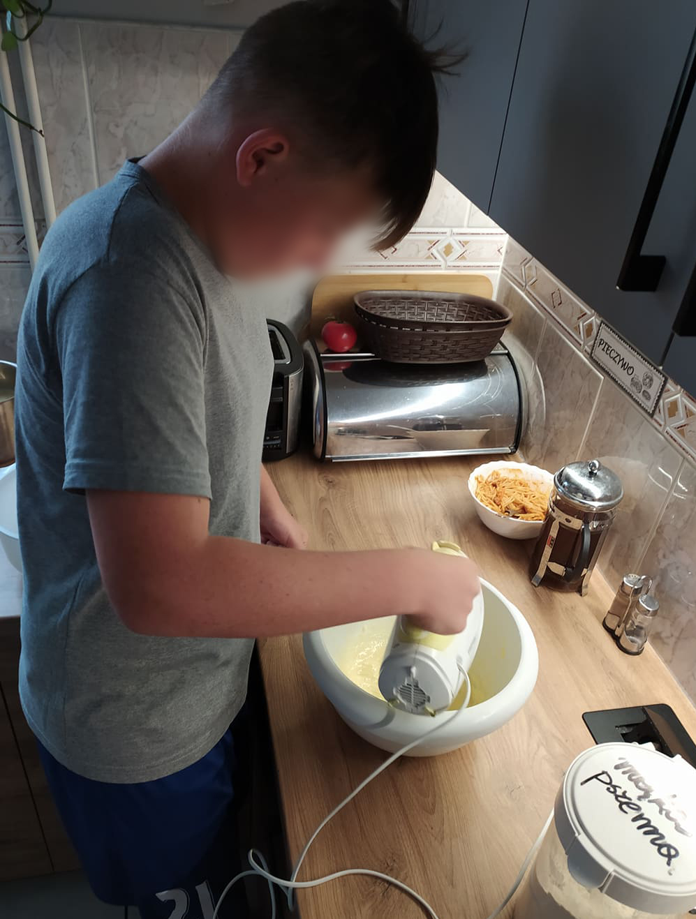 wychowanek miksuje ciasto przy kuchennym blacie